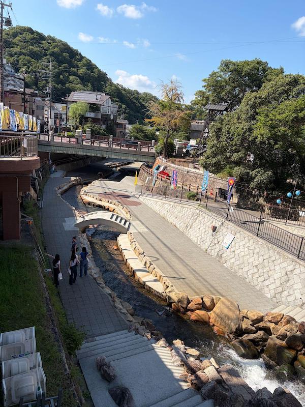 Arima River stone walkway and decorative arch bridge in the town center Walking is part of the experience because there is always something new around the next corner. A carbonated rice cracker shop may sit beside a meat shop, while an old building or small spring source appears farther up the hill. The town is compact enough to explore without following a strict itinerary.
