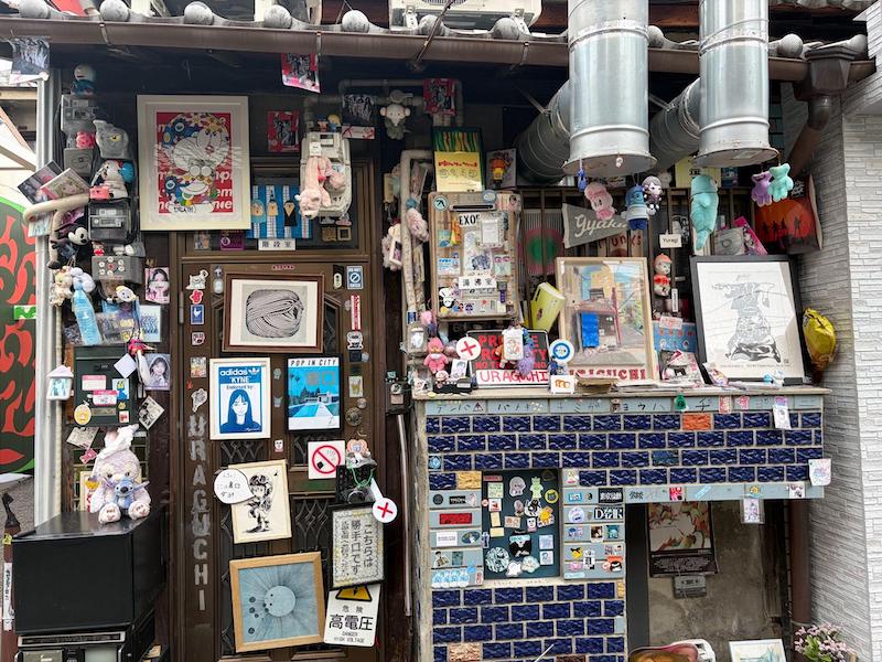Eclectic door and wall decorated with Japanese toys stickers and posters in Nakazakicho