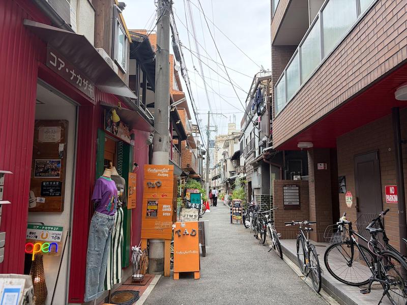 Narrow alleyway lined with independent vintage clothing shops and bicycles in Nakazakicho Osaka