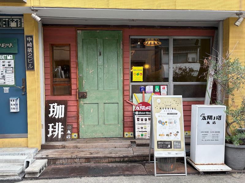 Weathered green wooden door and pastel exterior of Cafe Taiyo no To Honten in Nakazakicho